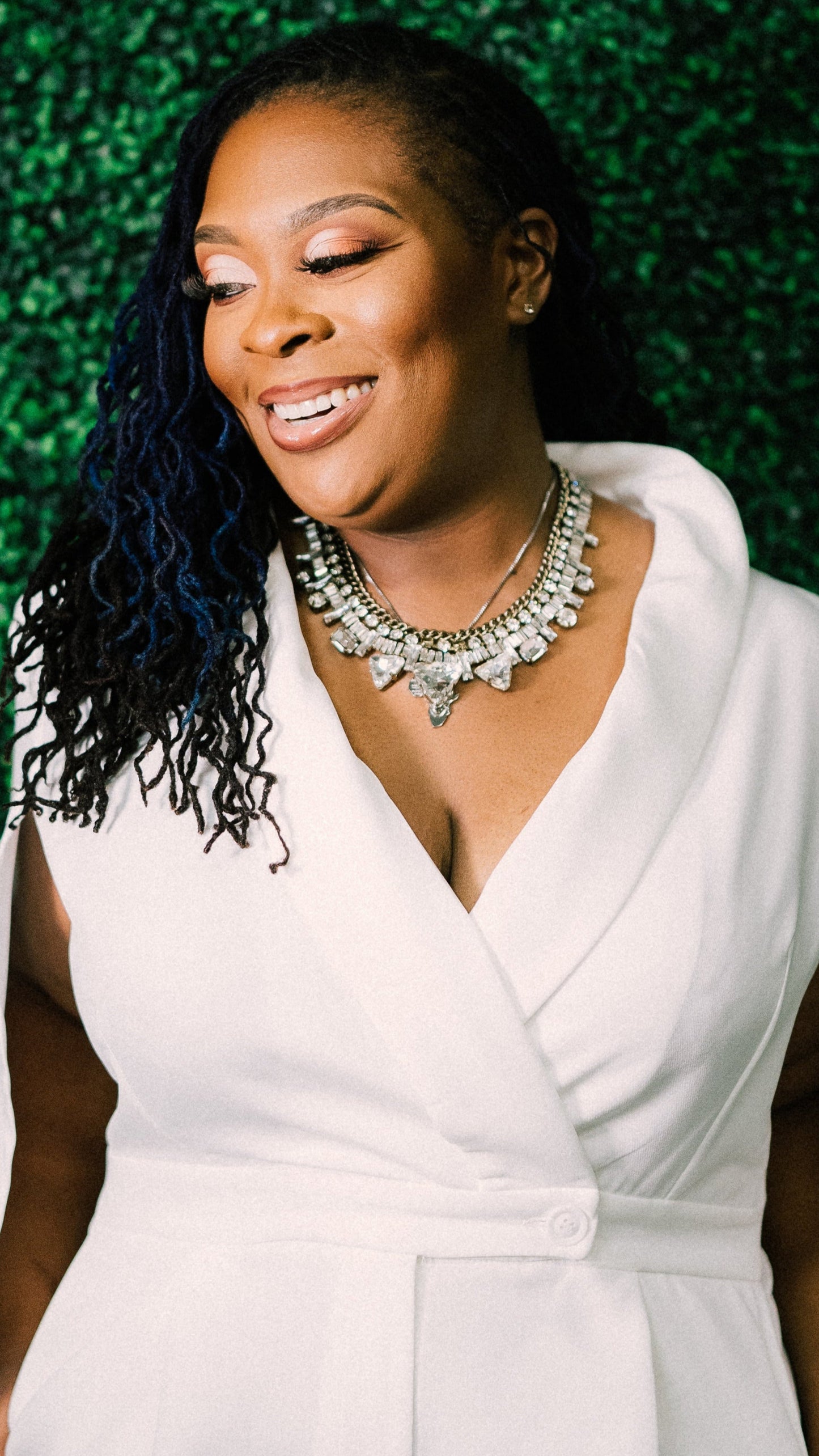 Woman in a white outfit with a green leafy background